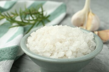 Sea salt in bowl on gray table, closeup