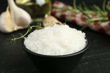 Sea salt and thyme in bowl on dark gray table, closeup