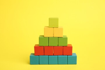 Pyramid of colorful cubes on yellow background