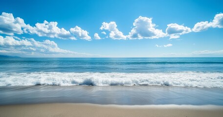 Gentle waves crashing on a sandy beach under a blue sky