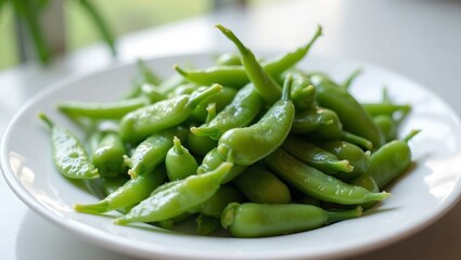 Fresh green snap peas on white plate glistening with water droplets in soft natural light