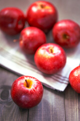 Bright red apples on a wooden surface with a blurred background and one apple in the foreground.