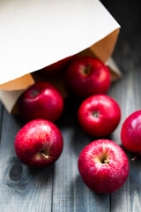 Bright red apples on a wooden surface with a blurred background and one apple in the foreground.