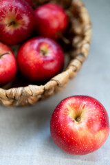 Bright red apples on a wooden surface with a blurred background and one apple in the foreground.