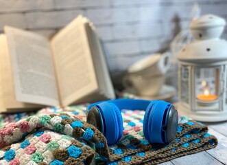 Cozy autumn or winter photo with crochet blanket, flashlight and blue headphones	
