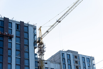 A construction crane in front of a high-rise building. An apartment building is under construction.