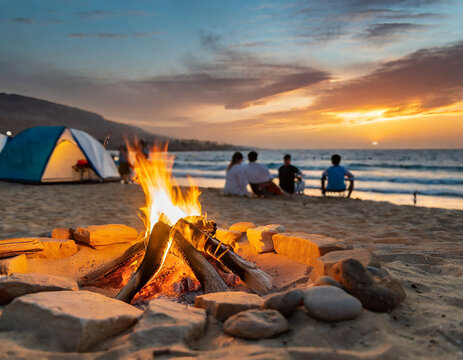 Relaxing beach bonfire at sunset with friends gathered near the glowing campfire on sandy shore