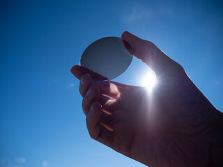 photochromic lens held in hand against the sun, photochromic lens exposed to sunlight becomes darker