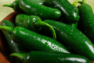 fresh padron pepper, raw, in a wooden bowl, on the table, there are no people.