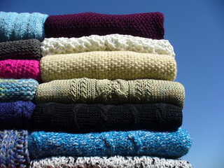 Hand-made warm sweaters and vests from various types of yarns evenly arranged - composition with...