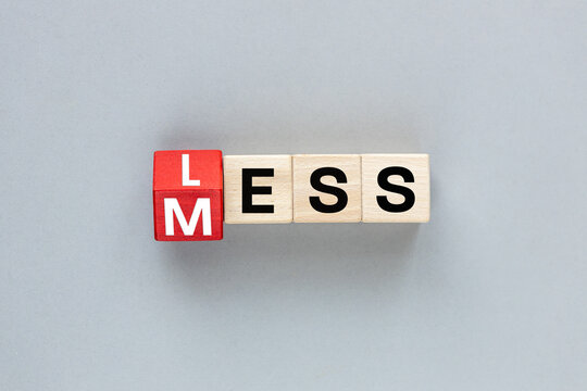 The words LESS MESS. Motivation to make less mess. Cubes form the expression less mess, flat lay, copy space, grey background