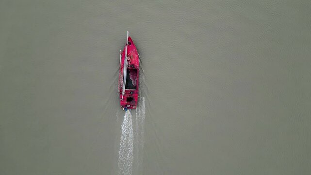 Top view of an empty red bulkhead ship moving forward through the water