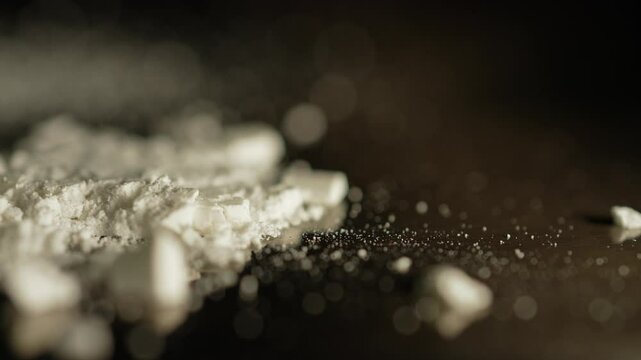 Macro close up at moving crushed drug cocaine powder substance. Opioid crises abuse and addiction. Hard addictive illegal drugs.