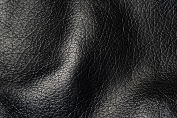 A close-up of genuine black leather. A detailed view of the surface of genuine black leather, showcasing fine lines and natural curves. This texture exudes a sense of luxury and durability.