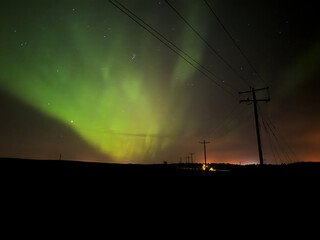 The Aurora Borealis glows green above the North Dakota landscape and power lines