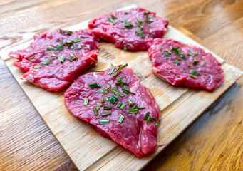 Sliced raw rib eye steak with rosemary and olive oil