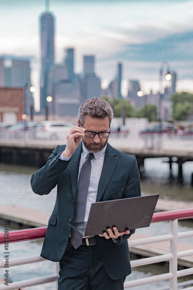 Wall mural Middle eastern millennial business man in suit working on laptop outdoor. Mature handsome businessman working on his laptop outside in NY. Confident Entrepreneur using PC on the street.