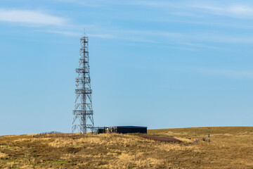Rural radio communication tower and control building in remote moor land countryside under clear...