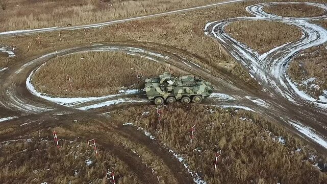 AERIAL VIEW: Armored Ukrainian personnel carrier training ground performs exercises to pass obstacles. Military equipment training ground in Ukraine. Training track at a military training ground