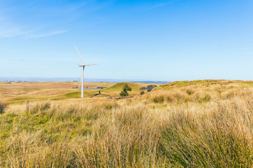 Fototapeta premium Hill and ancient hillfort site in open countryside contrasting old with new modern green energy wind farm turbines