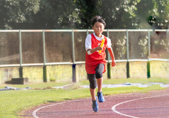 陸上大会でリレーを走る小学生の男の子