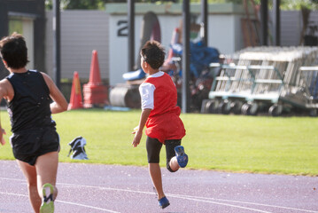 Obraz premium 陸上大会でリレーを走る小学生の男の子