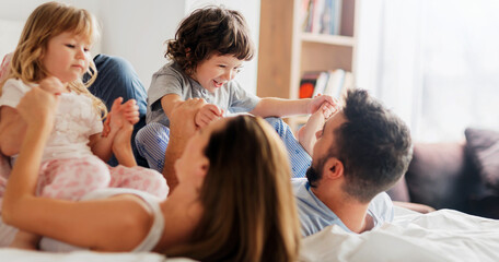 Fototapeta premium Family playing and laughing together in bed during the morning