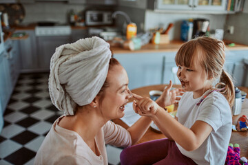 Mother and daughter having fun with chocolate during breakfast at home