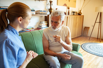 Obraz premium Female caregiver helping senior man at home