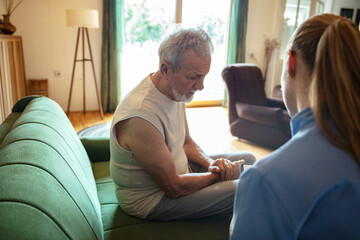 Obraz premium Female caregiver helping senior man at home