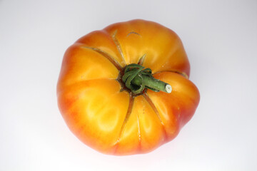 Tomato fruit with cracks on a light background. Pineapple Organic Heirloom Tomato