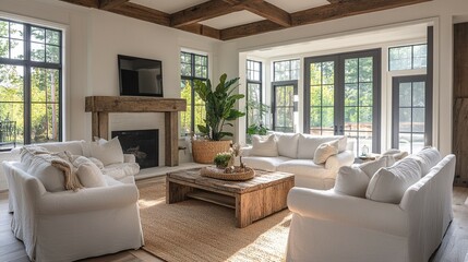 Bright living room with white sofa and chair, wood beams, and a fireplace in a modern farmhouse style.