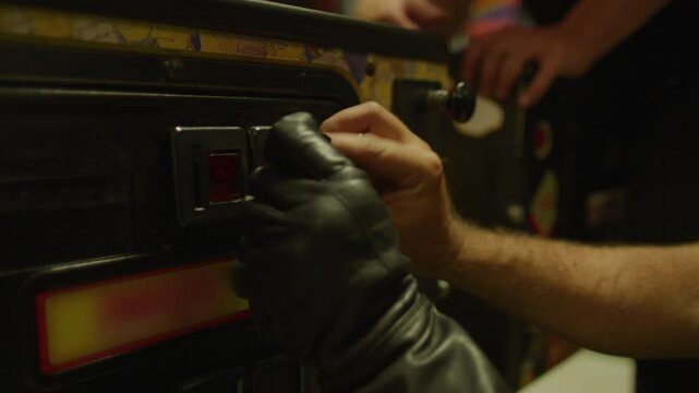 Man's hand putting coins into pinball machine - close up