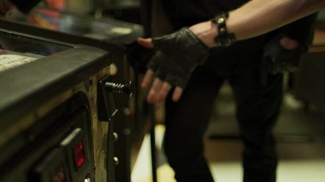 Man's hand pulling pin on pinball machine - closeup