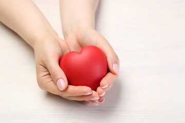 Woman with red decorative heart at white wooden table, closeup