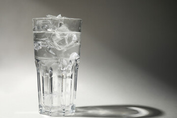 Refreshing water with ice in glass on grey background. Space for text