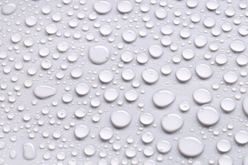 Water drops on light gray background, closeup view