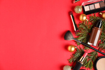 Flat lay composition with makeup products and Christmas decor on red background, space for text