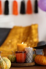 Burning candles and pumpkins on wooden table indoors, space for text. Halloween celebration