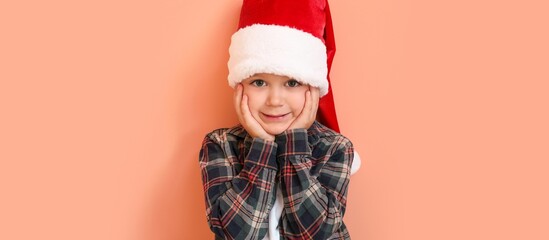 Little boy in Santa hat on color background