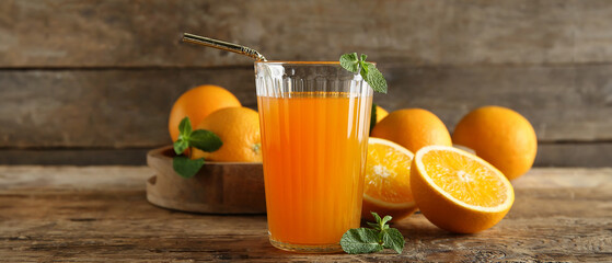 Glass of fresh orange juice with mint and fruits on wooden background