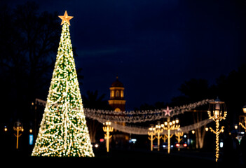 Large illuminated Christmas tree with twinkling lights and glowing star against a dark sky, festive and magical.