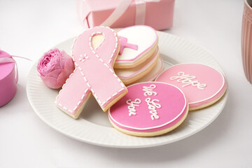 Plate with pink cookies and rose flower on white grunge background. Breast cancer awareness concept