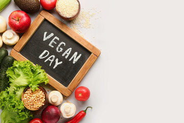 Board with text VEGAN DAY and different healthy products on grey background