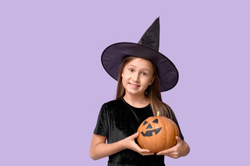 Cute little girl dressed for Halloween as witch with pumpkin on purple background