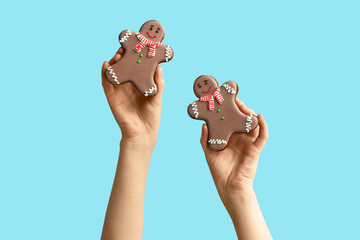 Female hands with Christmas sweet gingerbread cookies on blue background