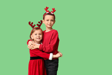 Cute little children in reindeer horns on green background