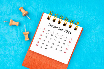December 2024 mini calendar with wooden thumbtack on blue.