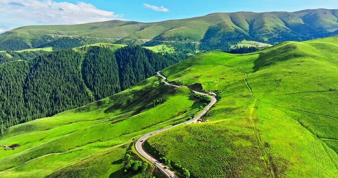 Country road and green grassland with mountain natural landscape in summer. Beautiful natural park scenery in Xinjiang, China.
