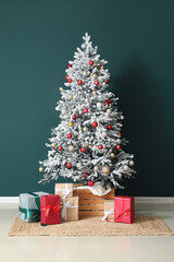 Decorated Christmas tree and beautiful gift boxes near dark color wall